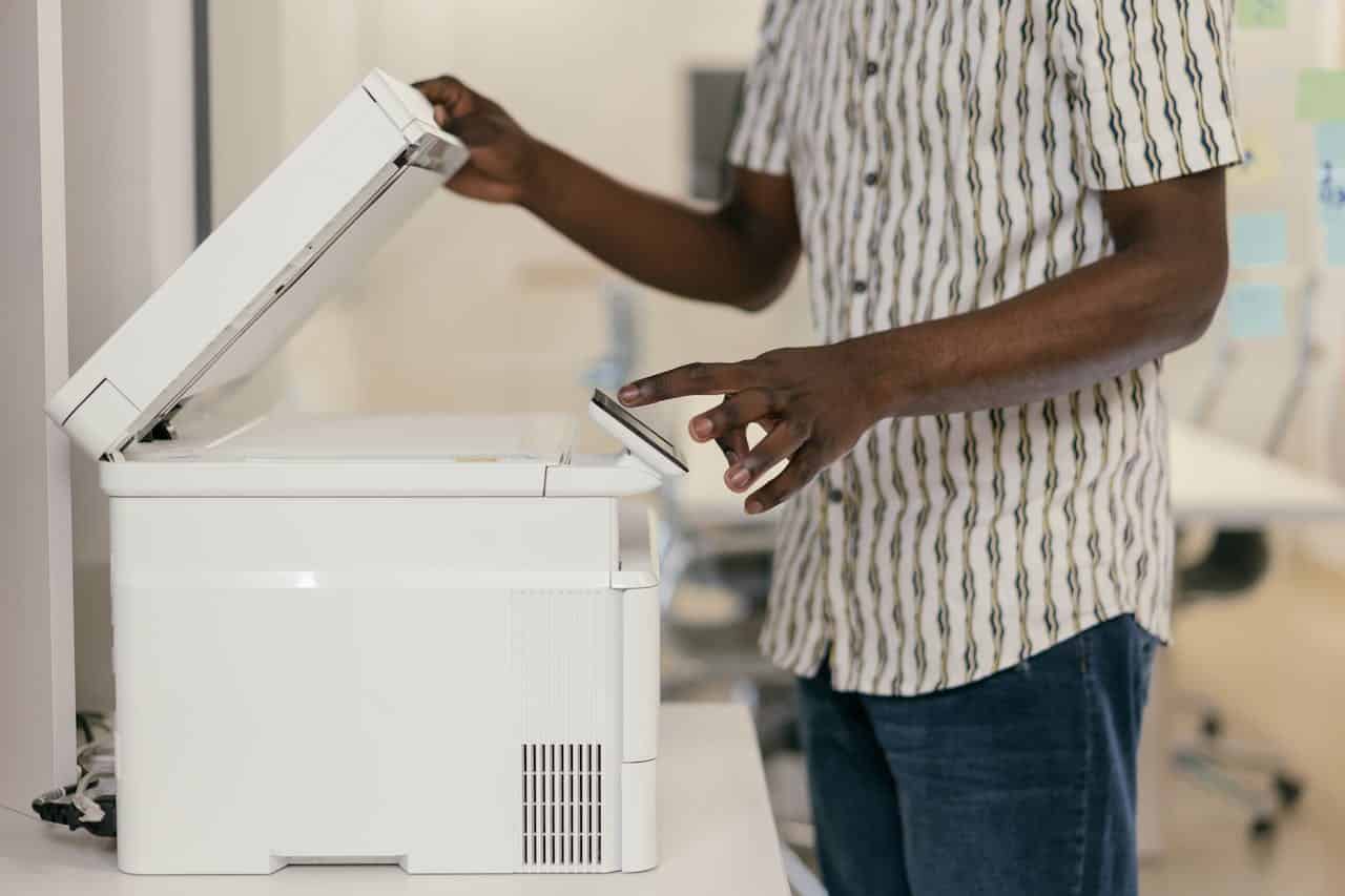 A person using an office printer with the lid open, preparing to make a copy.