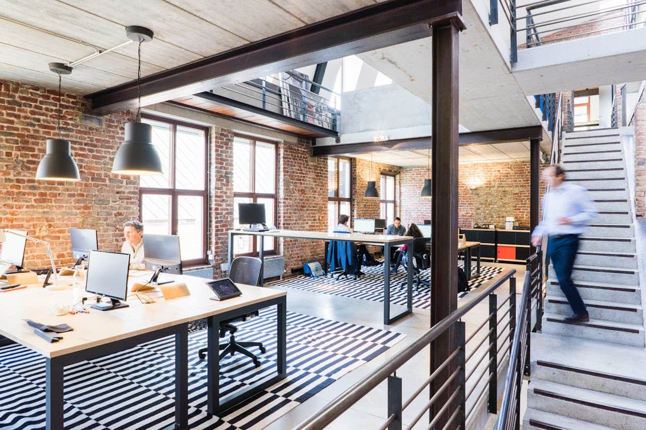 A spacious and stylish modern office with brick walls and large windows.