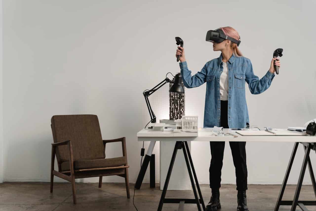 A woman wearing a VR headset and holding controllers in a modern workspace.