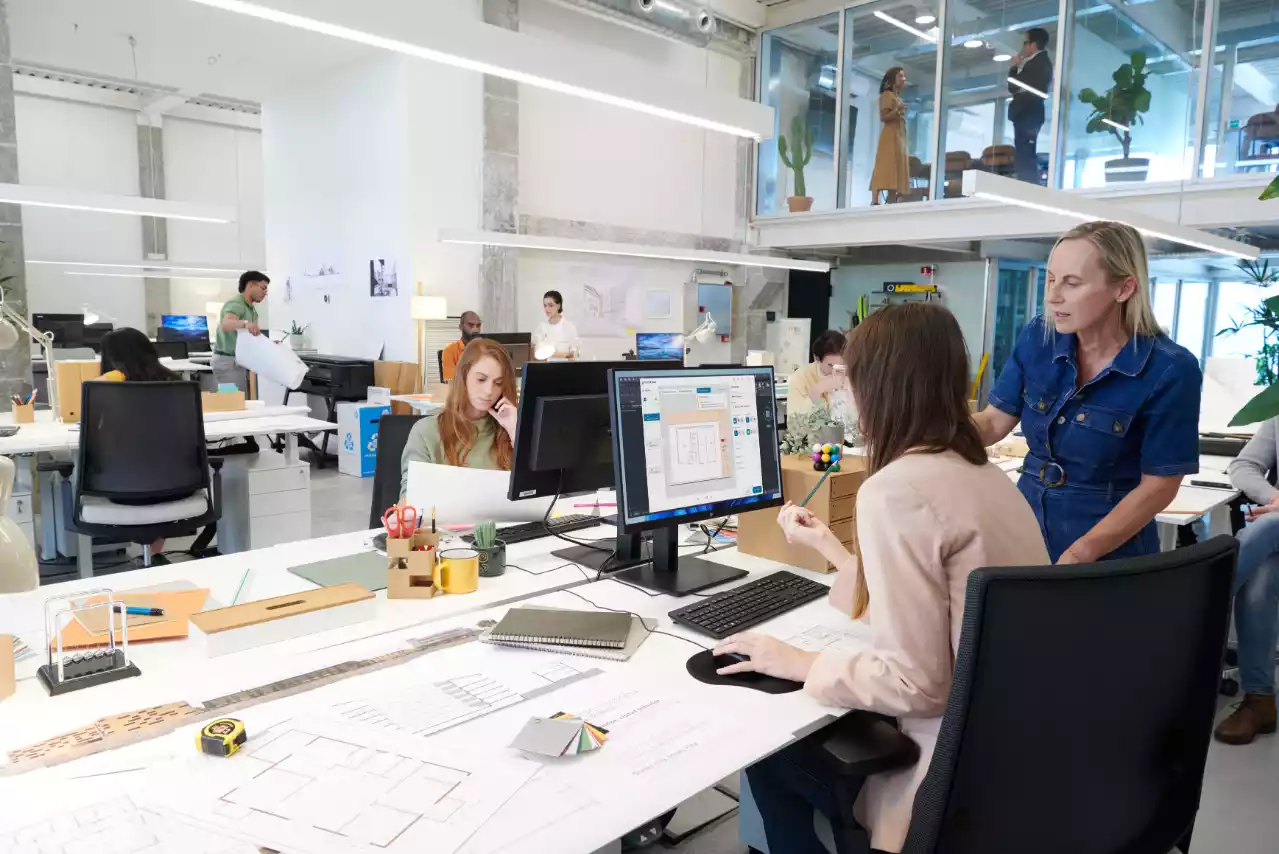 Diverse team working together in a modern office setting with computers and headsets.